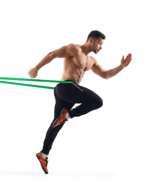 Side view of shirtless bodybuilder running in place using resistanve band. Muscular man with perfect tensed body posing, isolated on white studio background. Concept of bodybuilding.